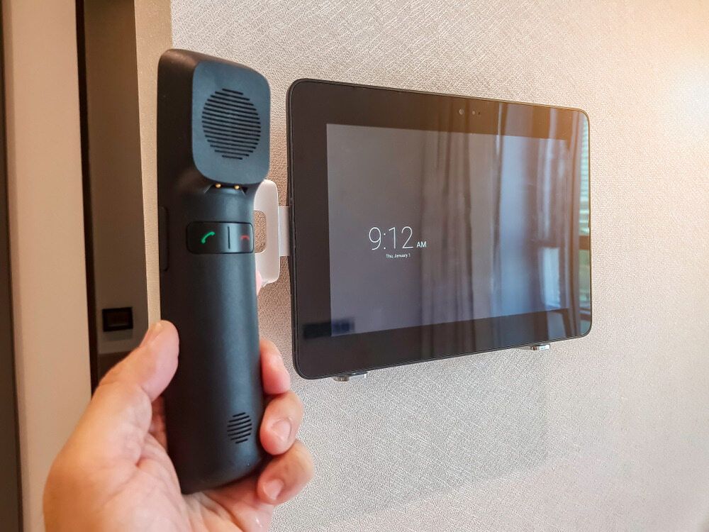 A Hand Holding a Black Intercom Handset Next to a Mounted Tablet — Flexicoms Communications in Ingham, QLD 
