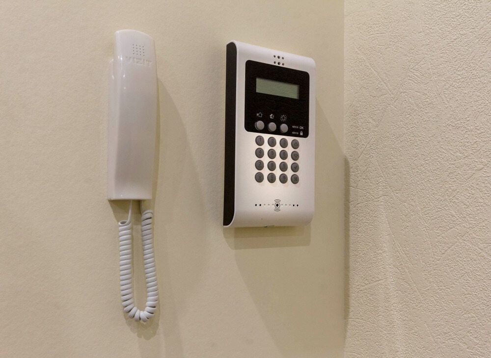 White Intercom and Handset Mounted on a Beige Wall — Flexicoms Communications in Ingham, QLD