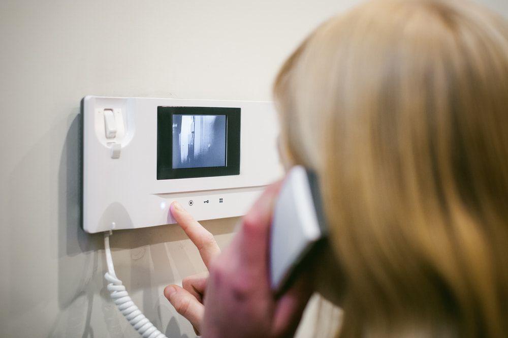 Woman Using an Intercom With a Screen, Pressing a Button — Flexicoms Communications in Tully, QLD