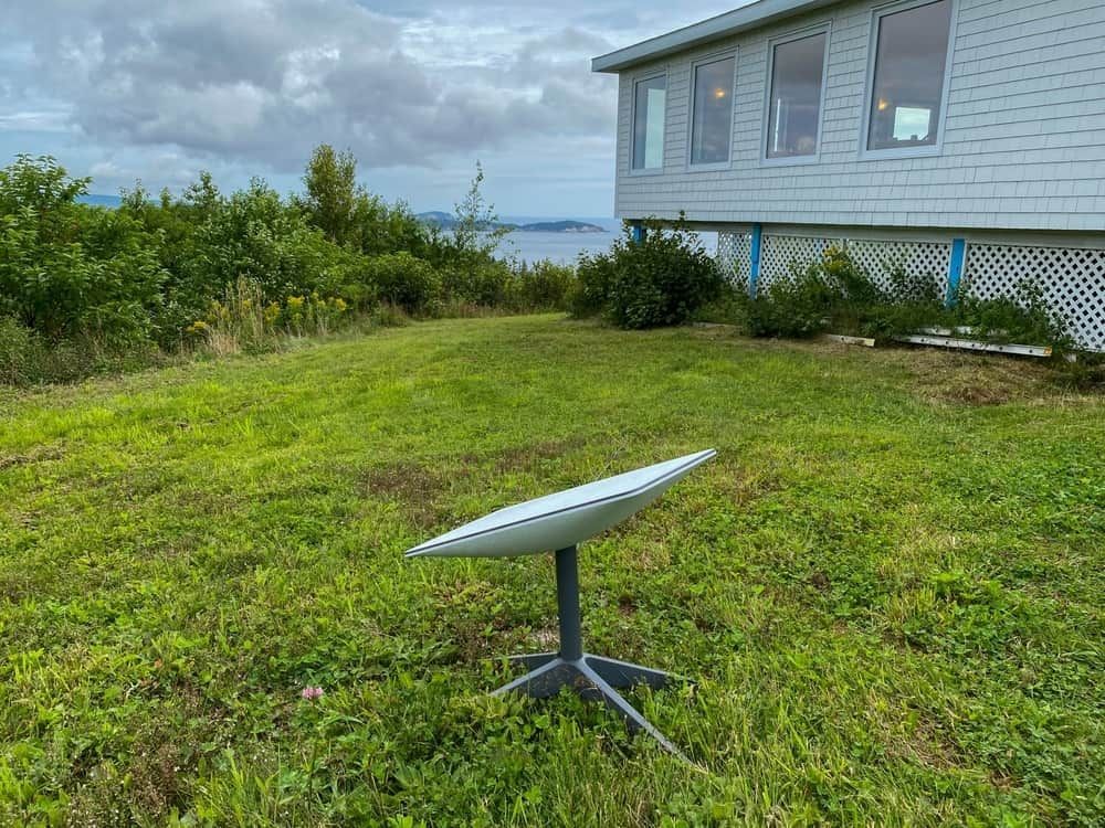 A Starlink Satellite Dish Sits on a Grassy Lawn in Front of a House — Flexicoms Communications in Ingham, QLD