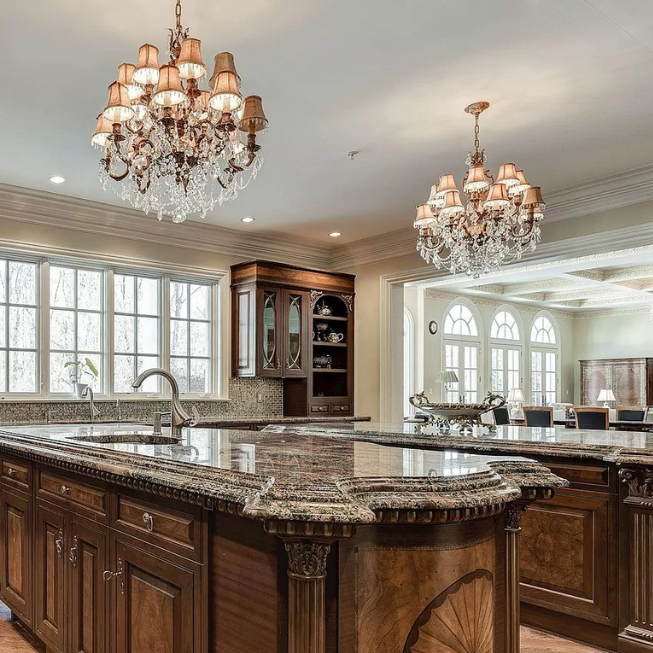 A kitchen with a large island and two chandeliers hanging from the ceiling A kitchen with a large island and two chandeliers hanging from the ceiling