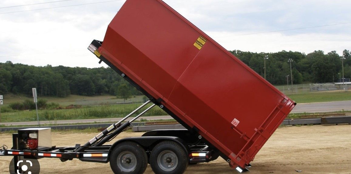 a red dumpster is sitting on a trailer in a field
