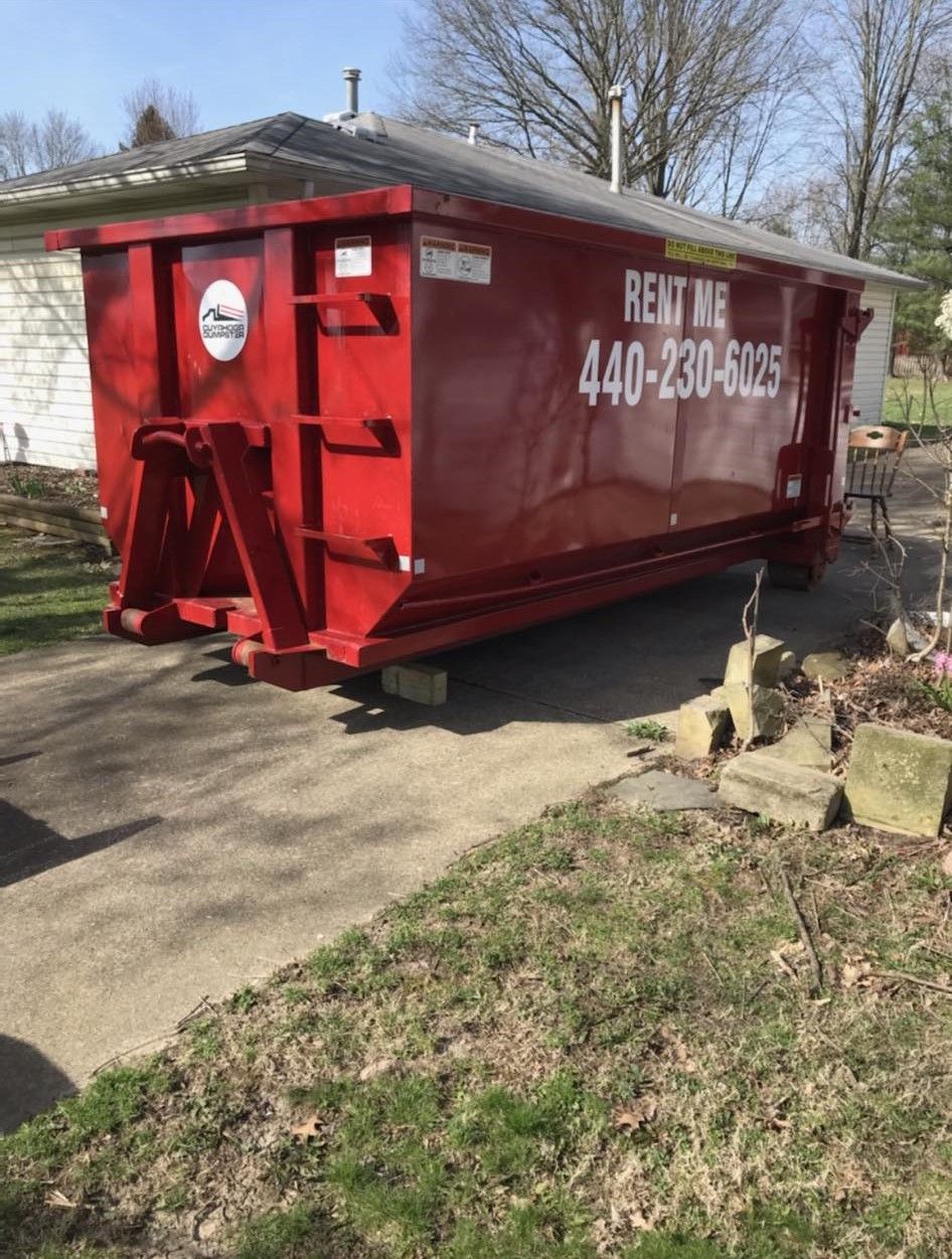 a red dumpster is parked in a driveway next to a house .