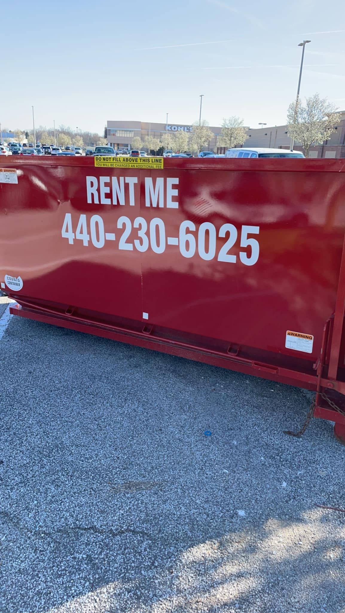 a red dumpster is parked in a parking lot .
