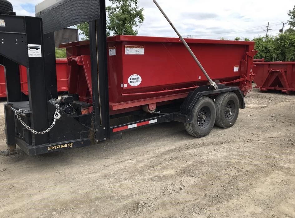 a red dumpster is sitting on top of a trailer .