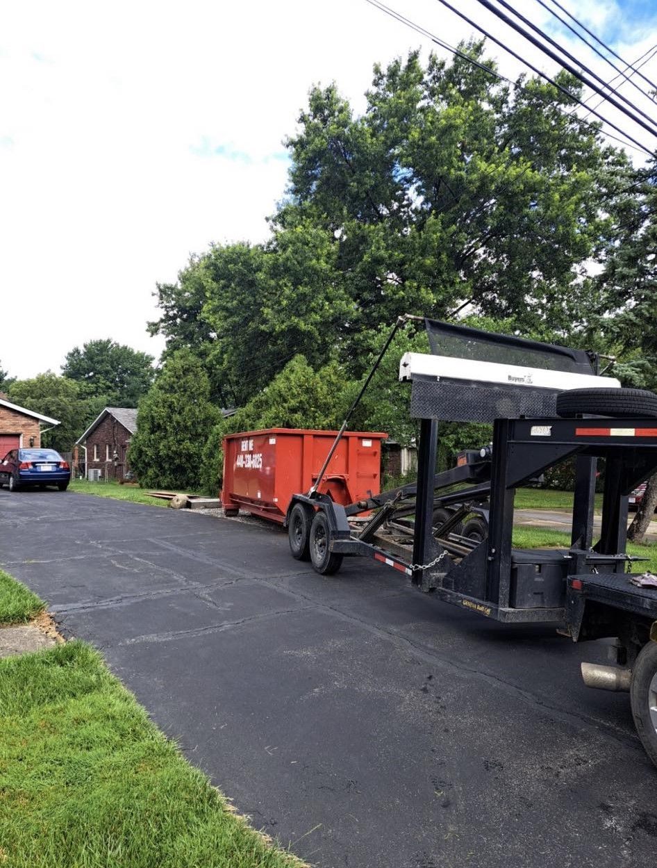 a dumpster is being pulled by a trailer down a street .