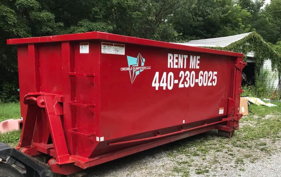 a red dumpster with the number 440-230-6025 on it