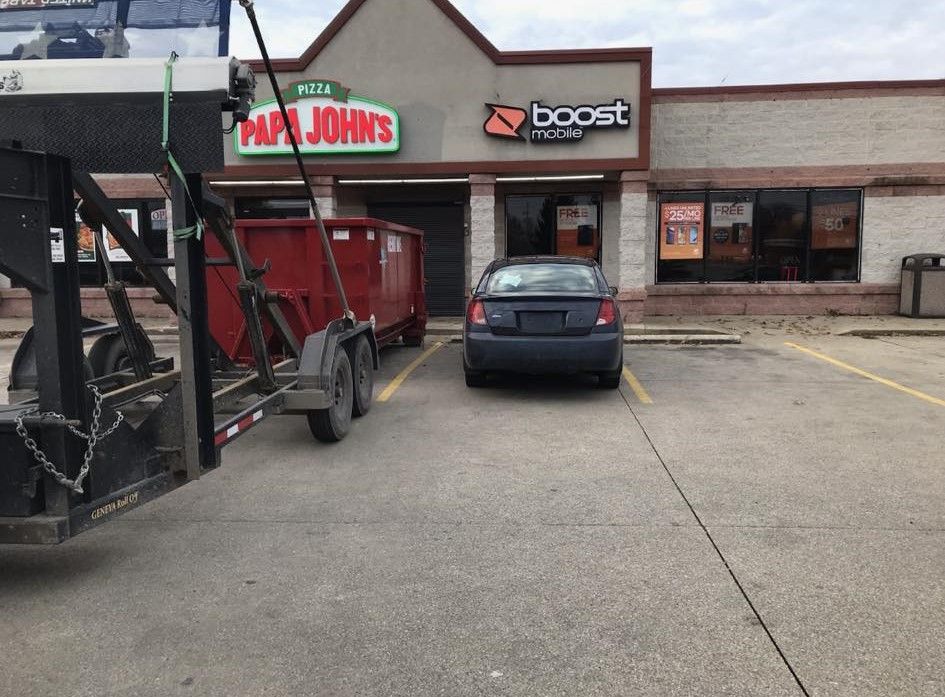a car is parked in front of a papa john 's restaurant