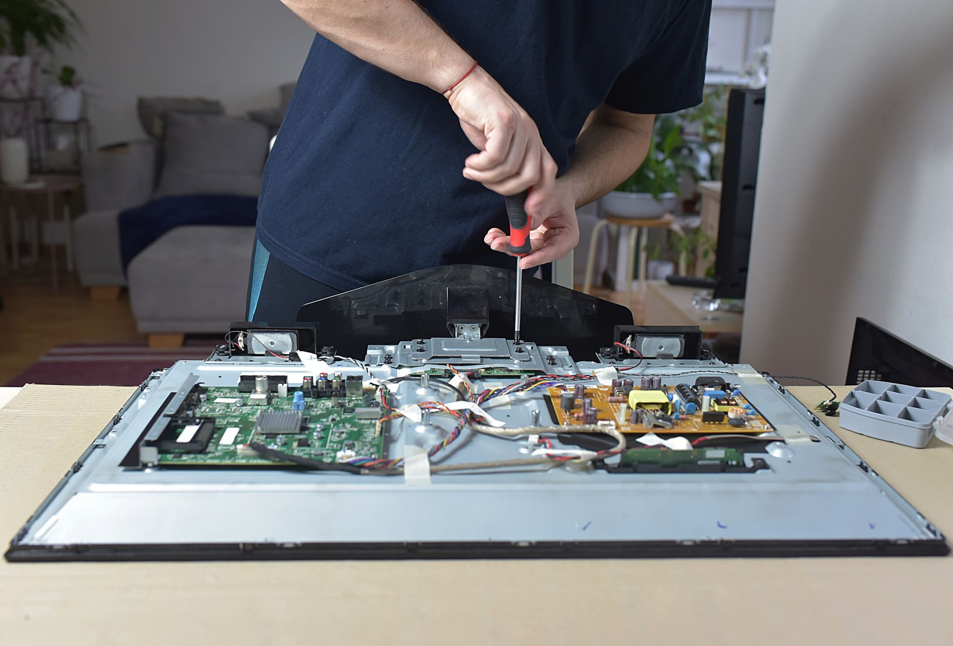 A man is fixing a flat screen tv with a screwdriver.