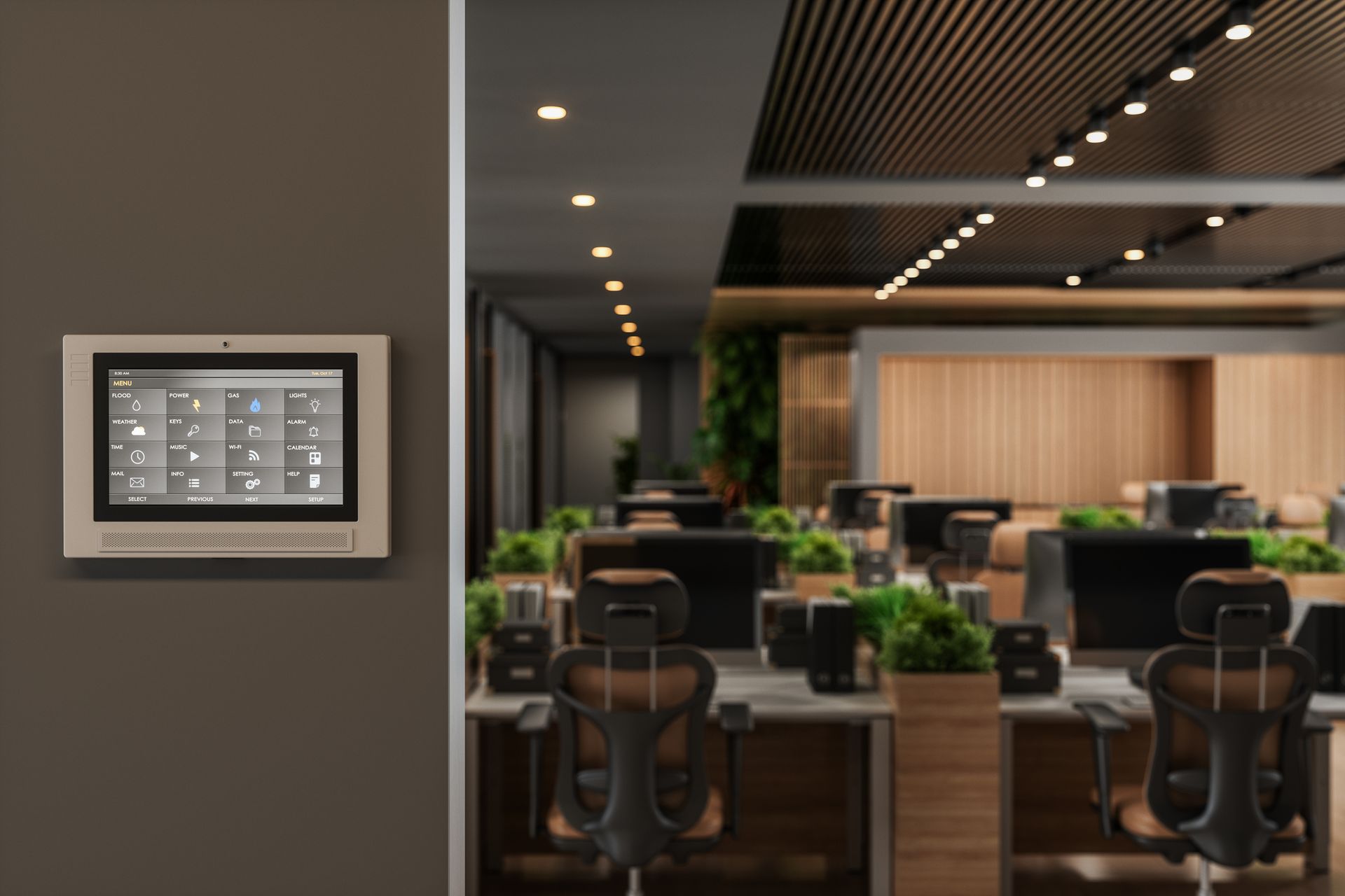 An office with lots of desks and chairs and a monitor on the wall.