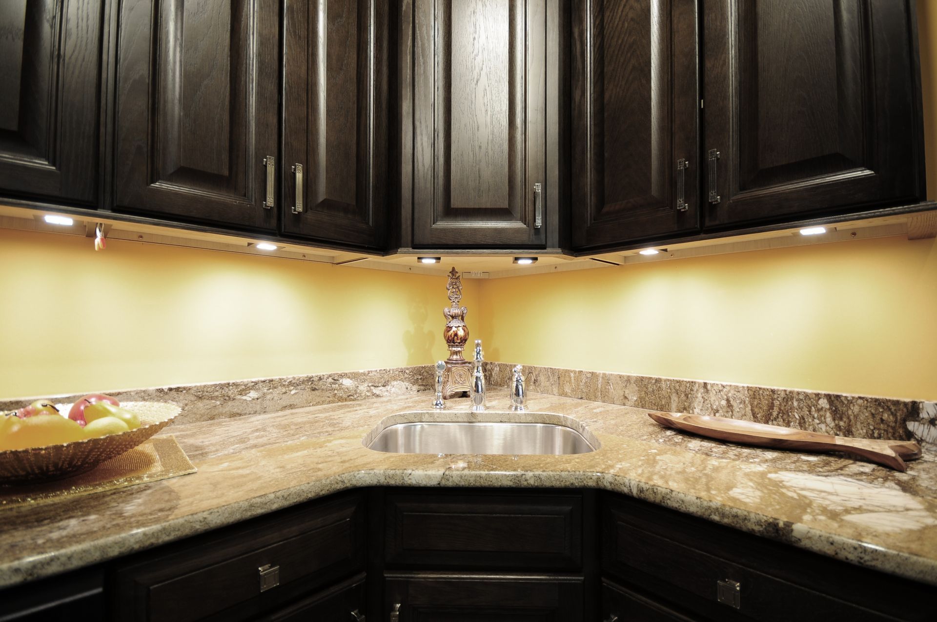 A kitchen with a sink and a bowl of fruit on the counter