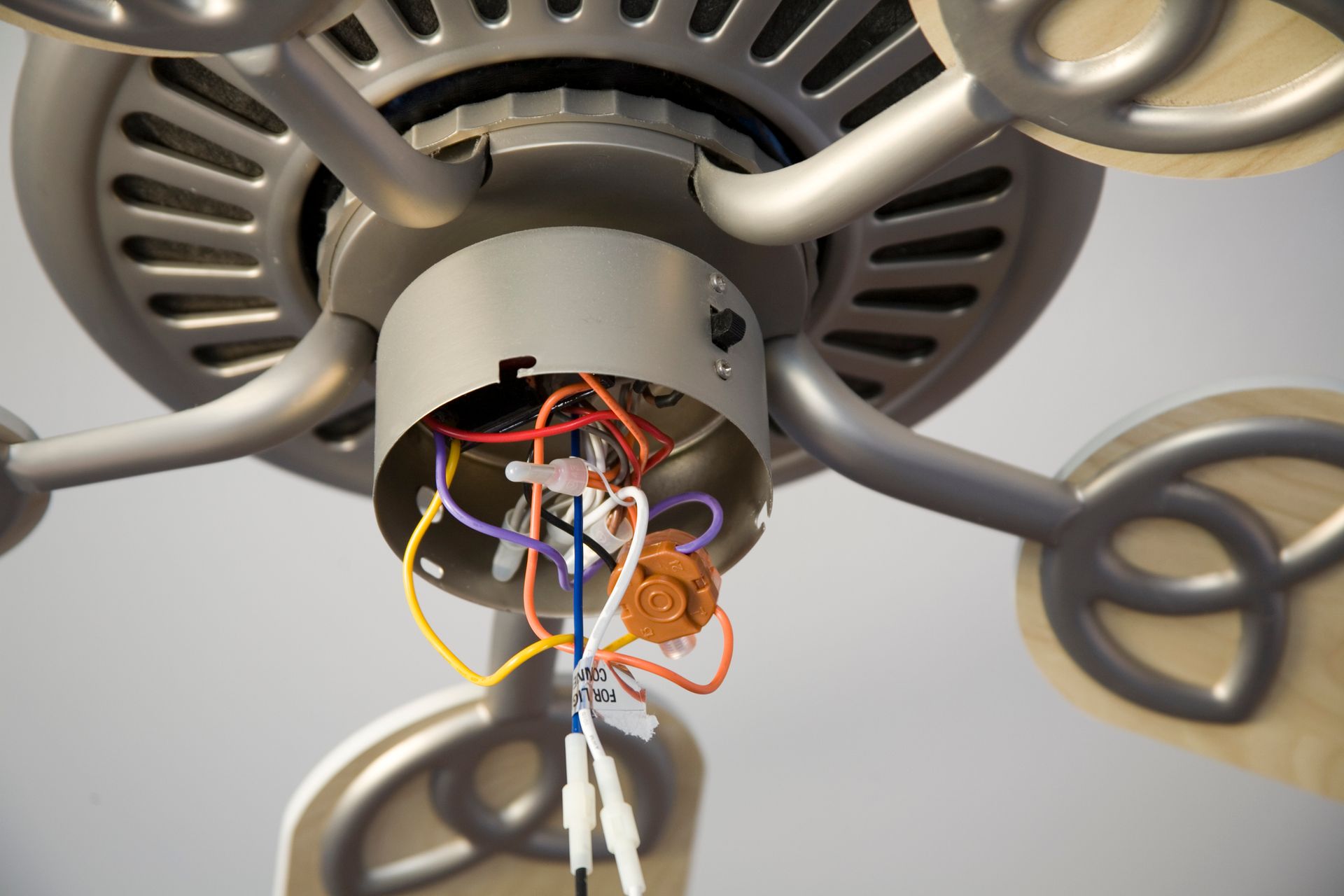 A close up of a ceiling fan with wires coming out of it
