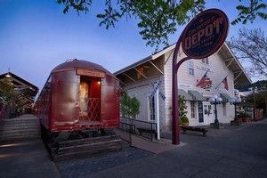 Red train car next to a white building with 