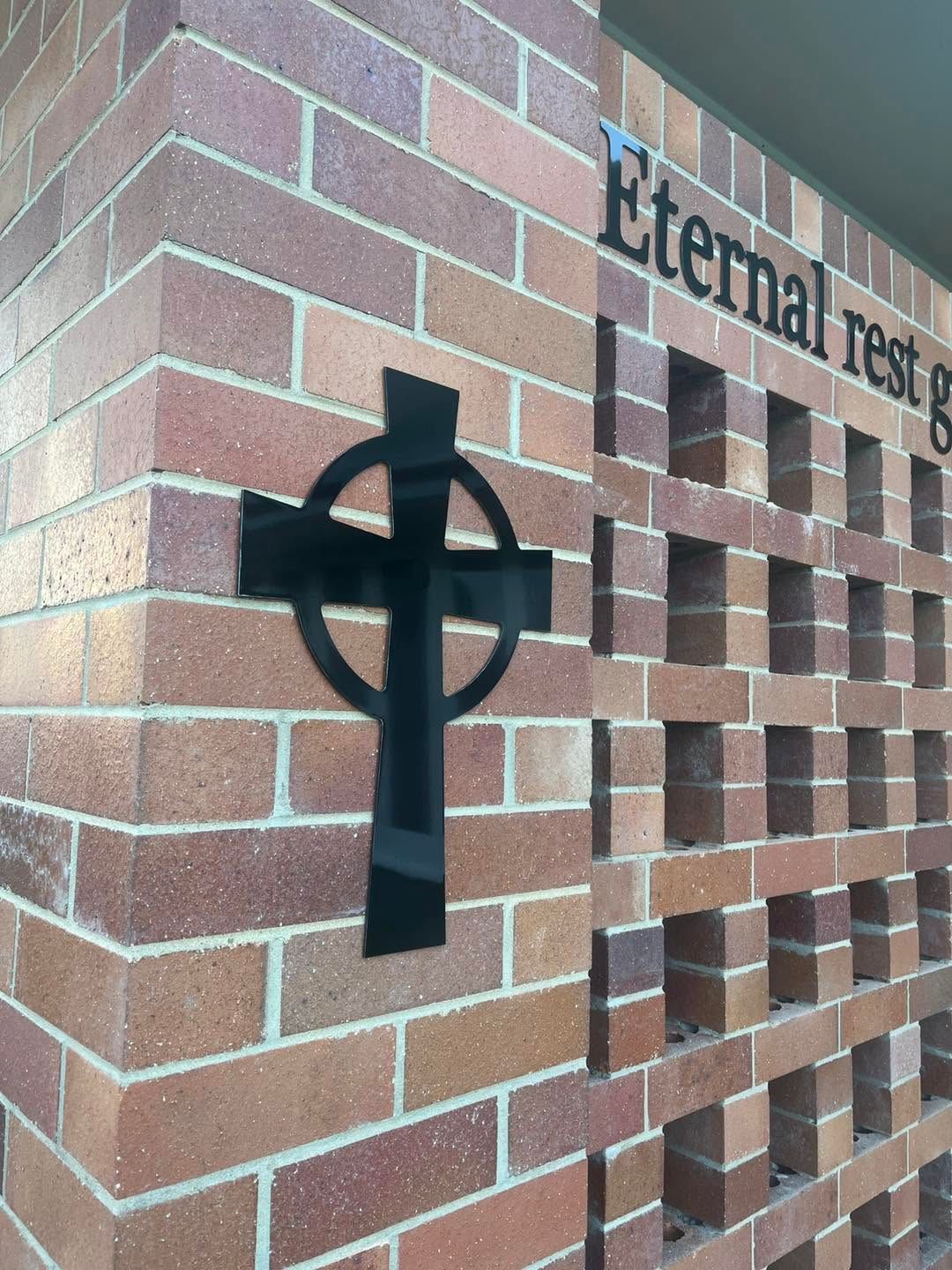 Black Cross Sign Mounted on A Brick Wall — Global Signage In Ingham, QLD