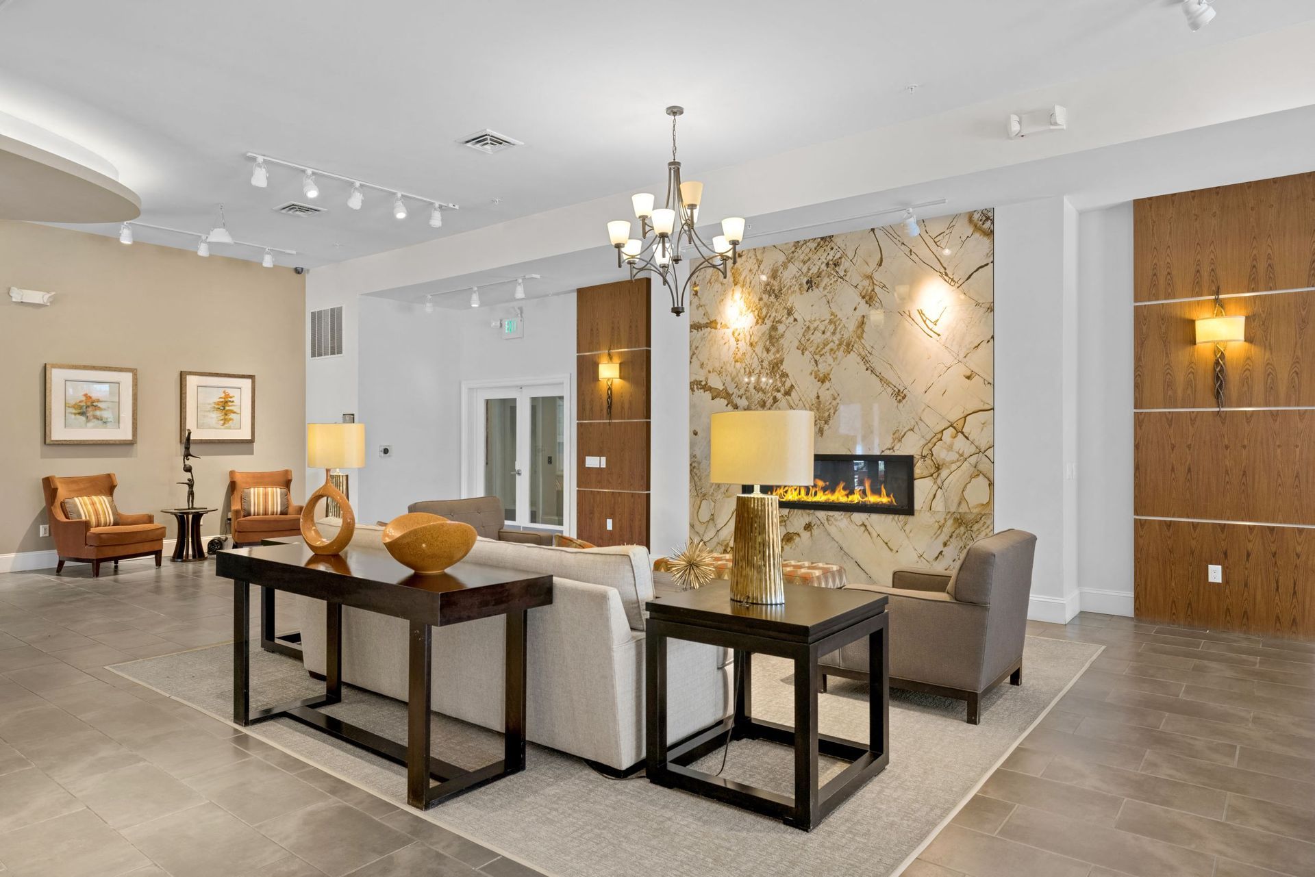 Lobby lounge with beige walls, sofa, armchairs, and a fireplace at The Parc at Greenwood Village.