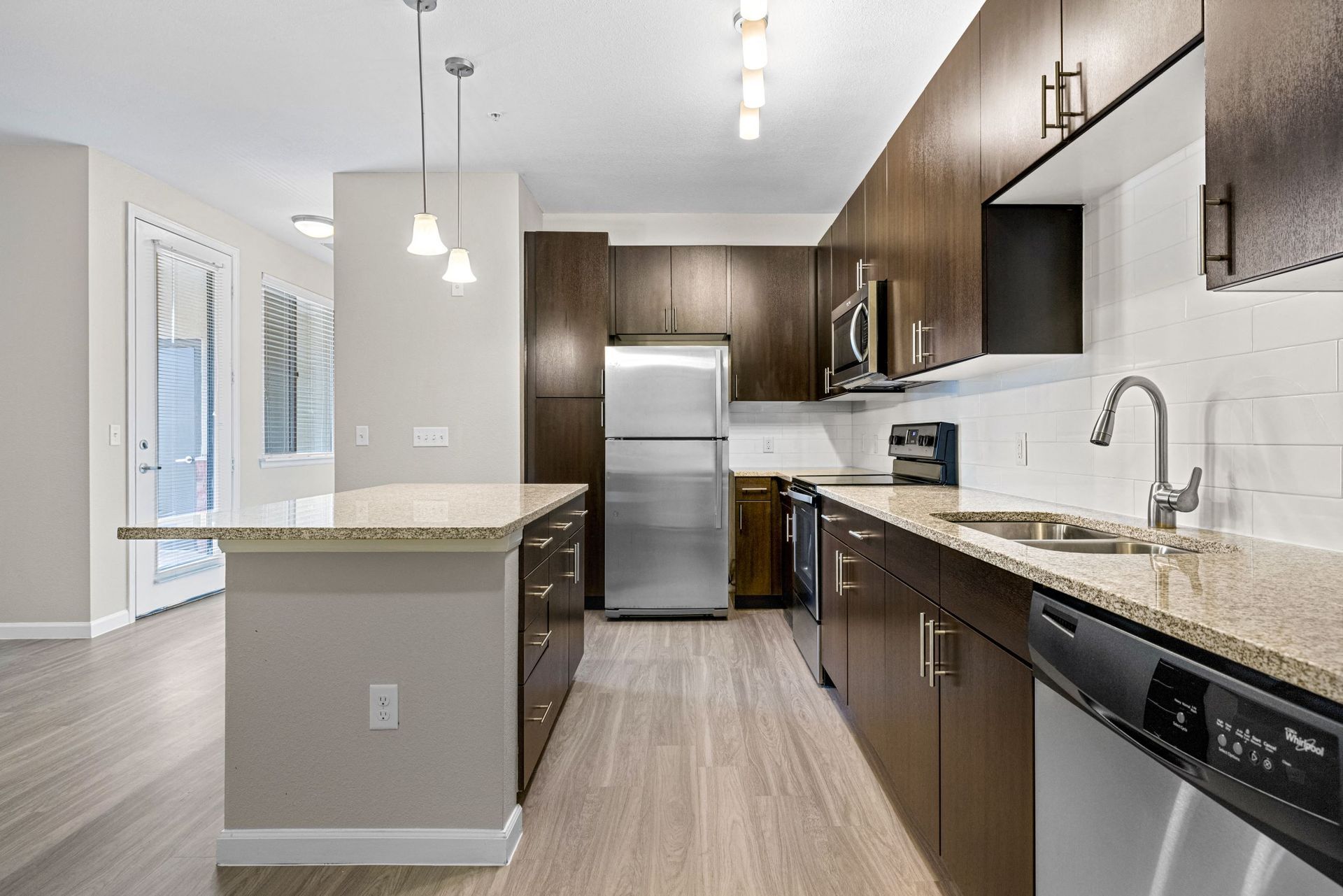 Modern kitchen with granite countertops, dark wood cabinets, stainless steel appliances and an island at The Parc at Greenwood Village.