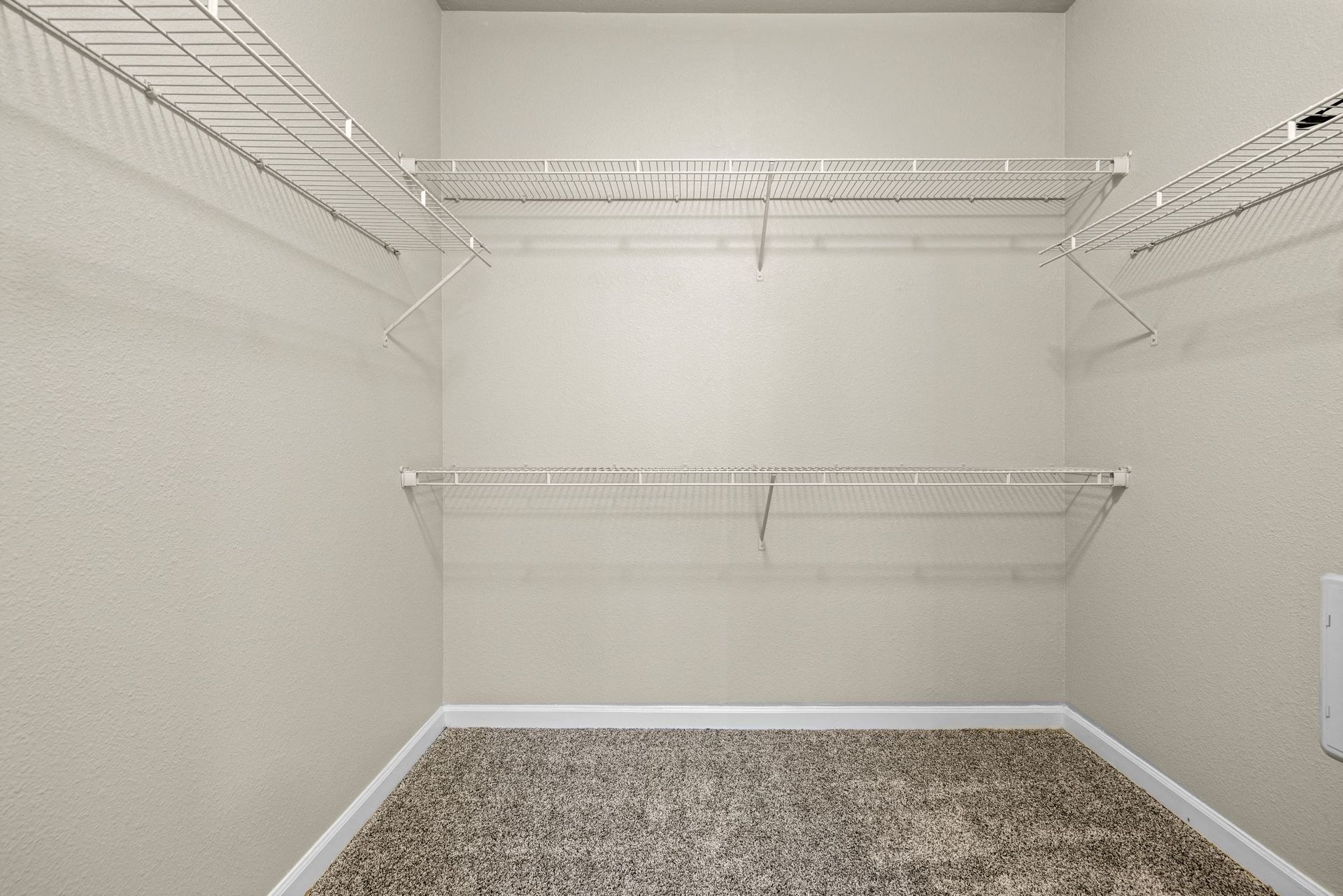 Empty walk-in closet with white wire shelves along beige walls at The Parc at Greenwood Village.