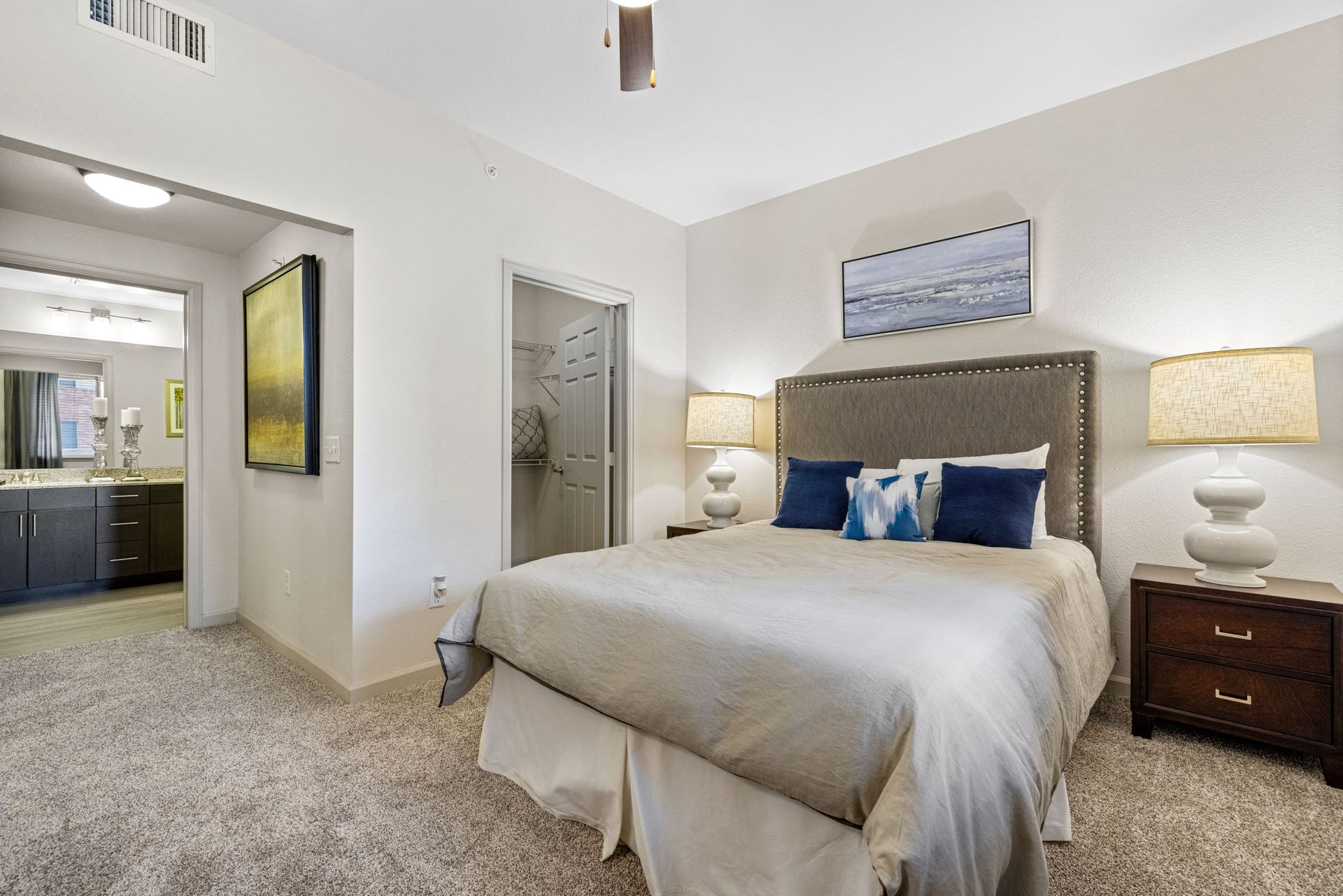 Bedroom with a large bed and tufted headboard, two nightstands with lamps, and a closet nearby at The Parc at Greenwood Village.
