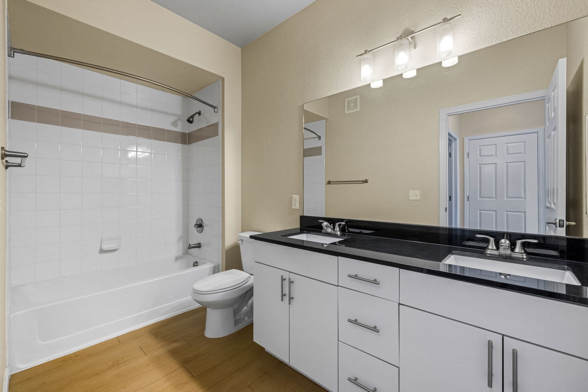 Bathroom with tub/shower, toilet, and double-sink vanity with a black countertop at The Parc at Greenwood Village.