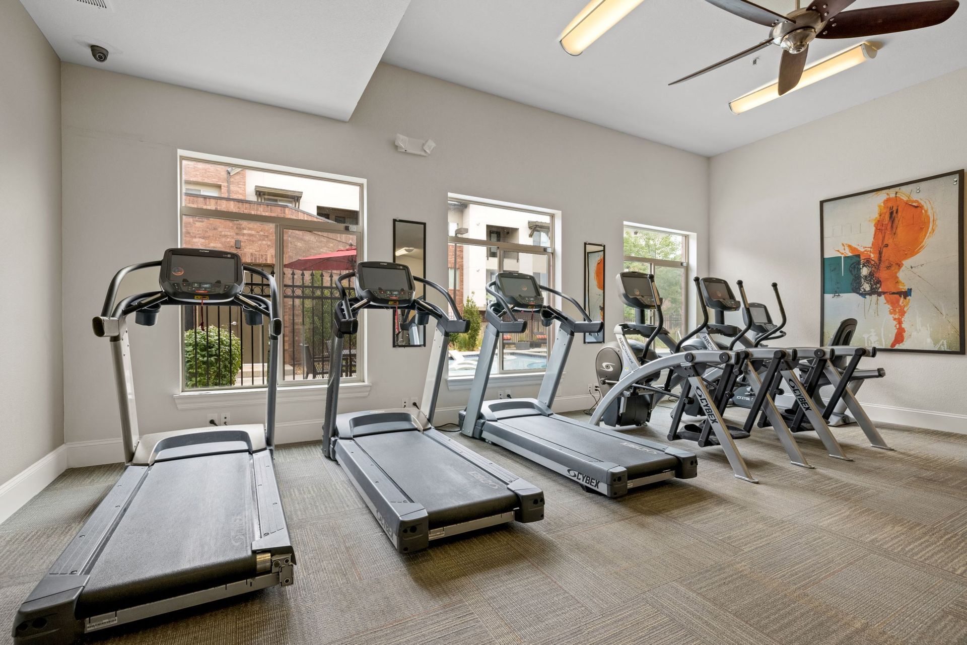 Fitness center with several treadmills and ellipticals by large windows at The Parc at Greenwood Village.