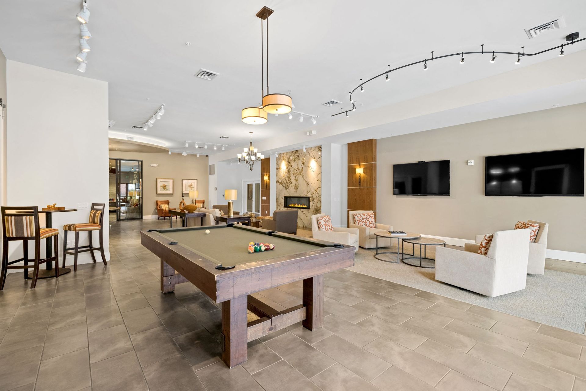 Spacious community lounge with a pool table, seating area, and wall-mounted TVs at The Parc at Greenwood Village.