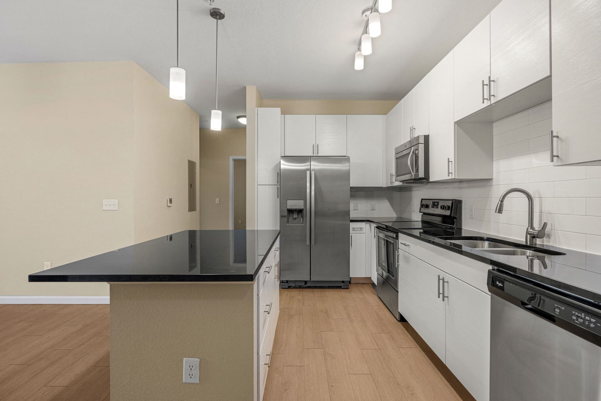 Modern apartment kitchen with white cabinets, stainless steel appliances, and a large black countertop island at The Parc at Greenwood Village.
