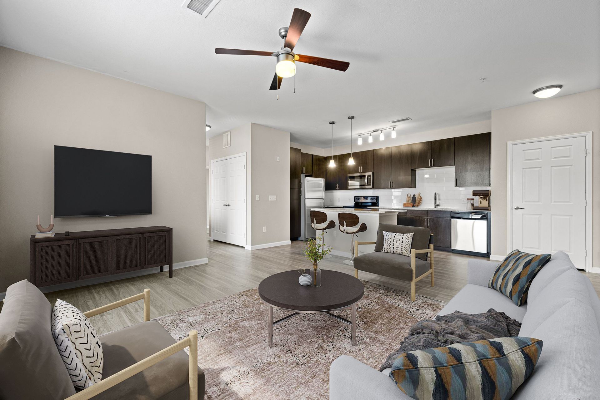Open-concept living area with a TV, sofa, and kitchen bar in a modern apartment at The Parc at Greenwood Village.