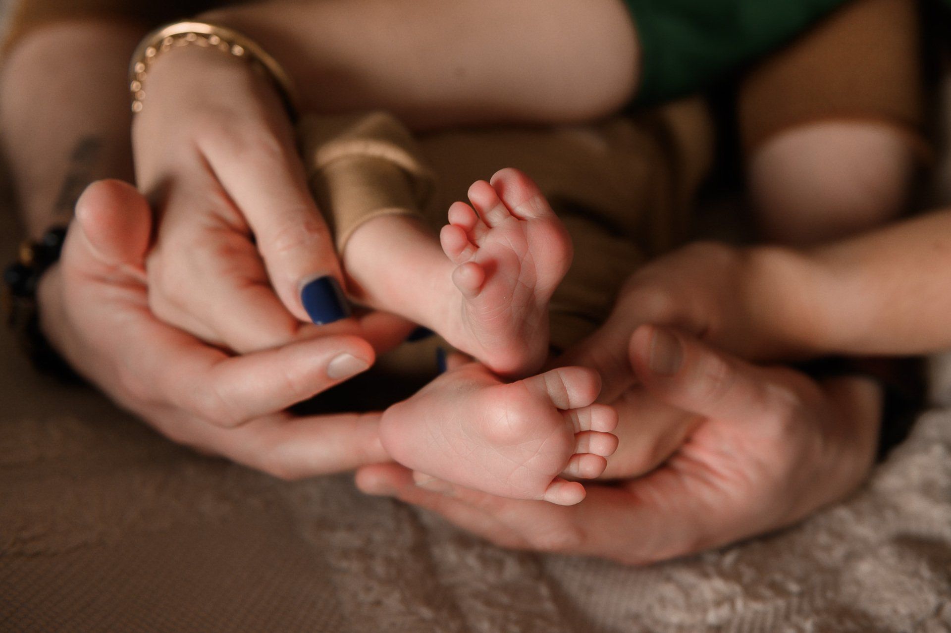 Handen die kleine babyvoetjes vasthouden, close-up met een neutrale achtergrond.