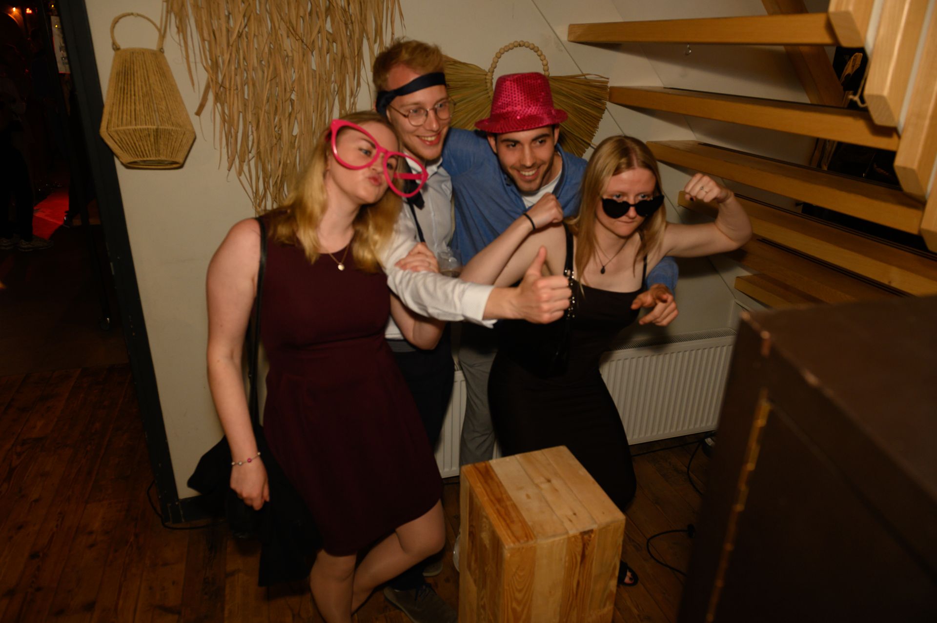 Vier mensen met feestmutsen en brillen poseren voor een foto.