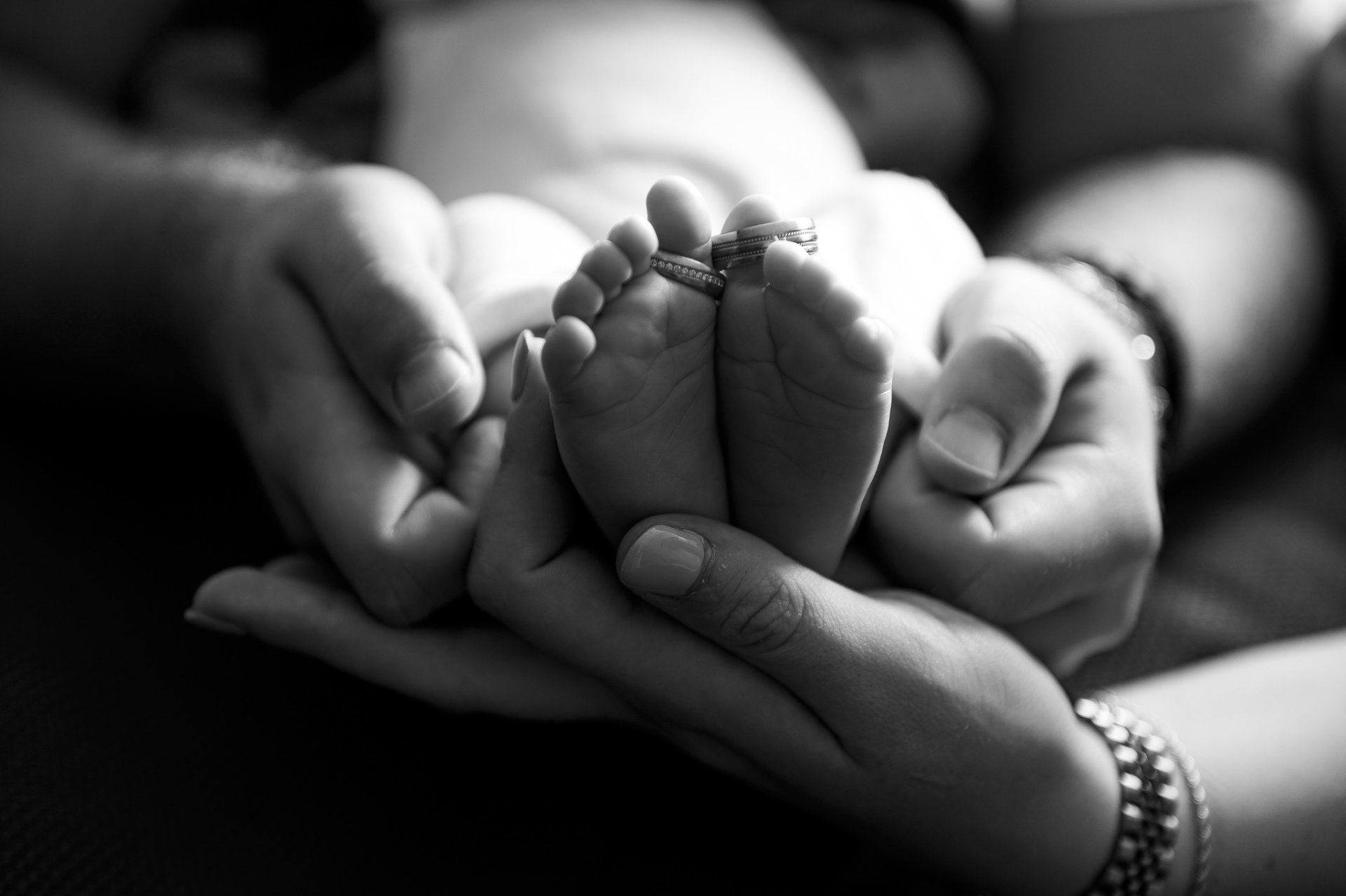 Handen wiegen kleine babyvoetjes, zwart-wit.