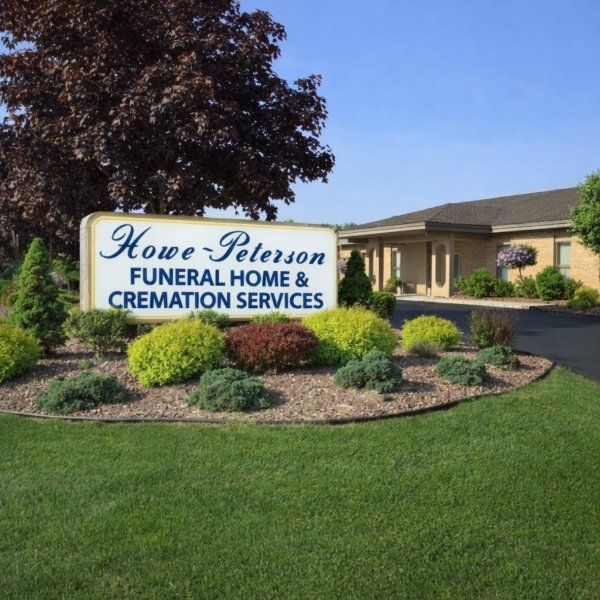 funeral home and cremations Taylor, MI sign at Howe-Peterson with landscaped shrubs and chapel building.