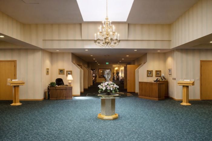 funeral home and cremations Taylor, MI lobby with chandelier, blue carpet and floral table centerpiece.