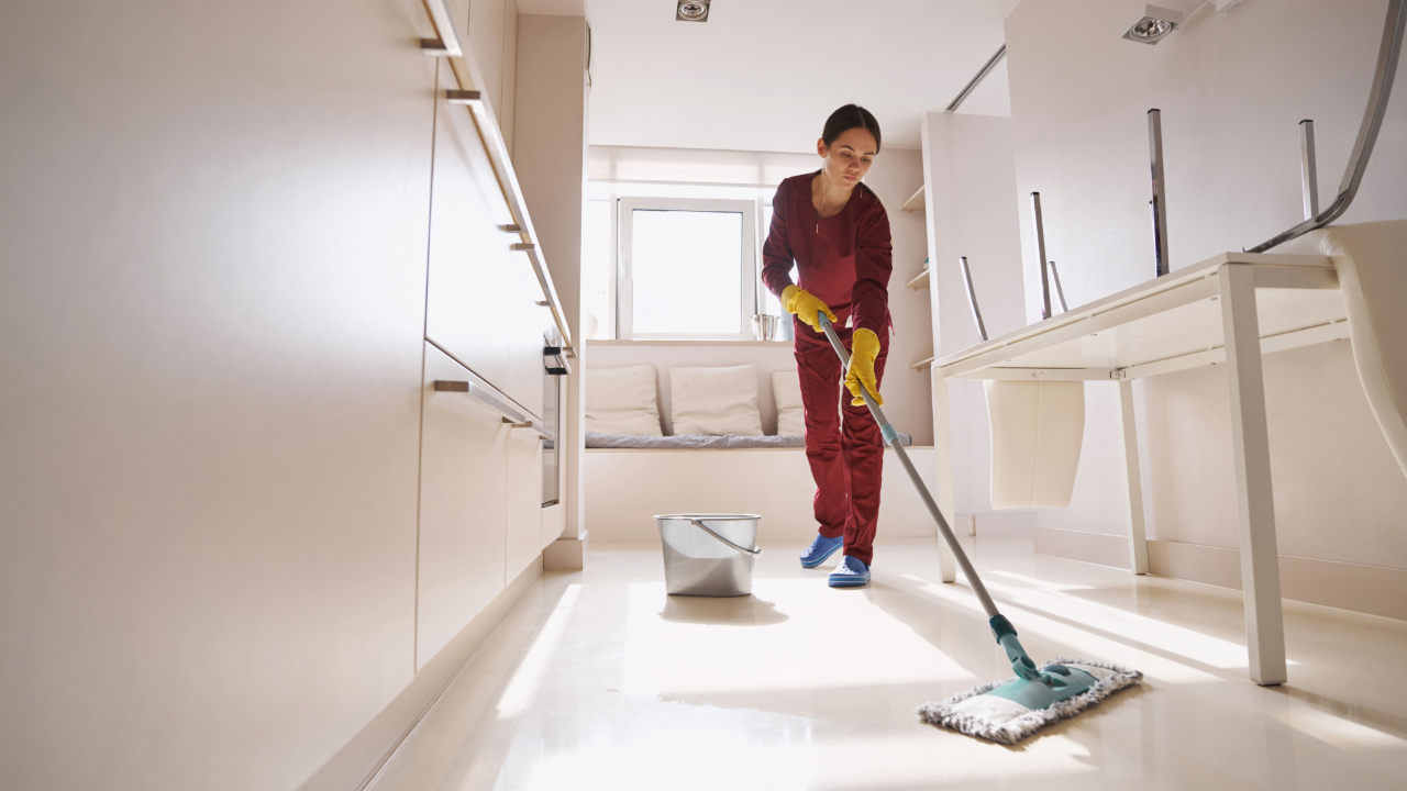 Residential cleaner mopping kitchen floor as part of standard house cleaning service
