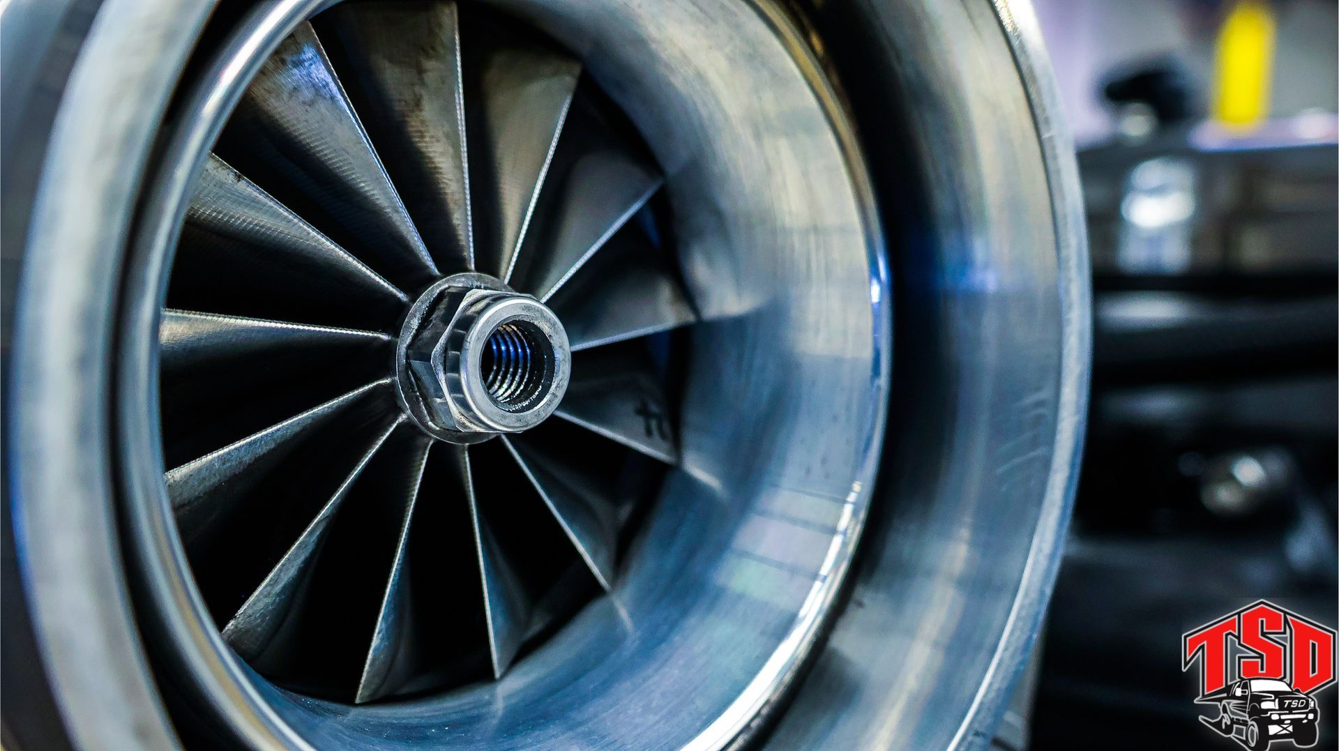 Close-up of a jet engine turbine fan blades spinning in metallic blue-gray tones