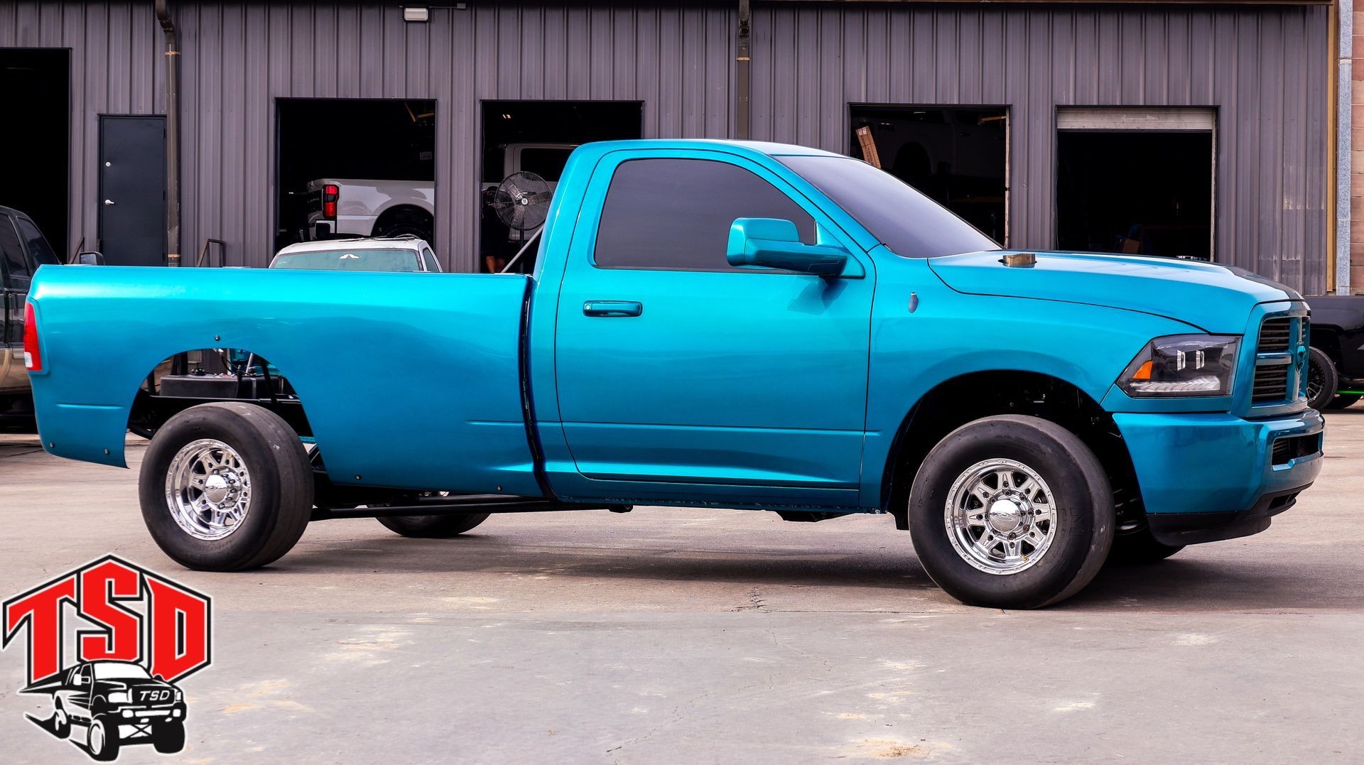 Bright blue pickup truck parked outside a garage