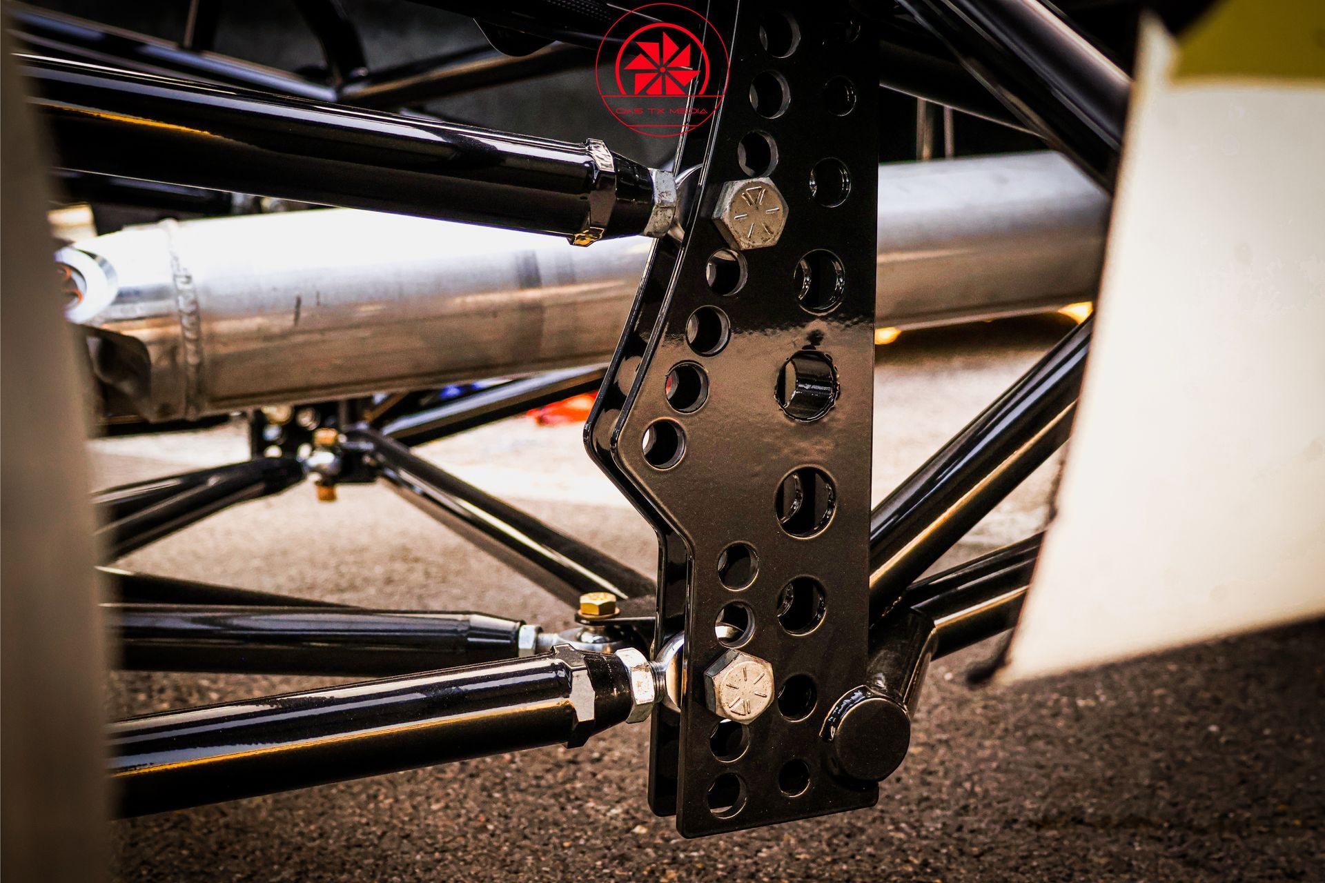 Close-up of a race car suspension and wheel assembly with black metal supports and white bodywork
