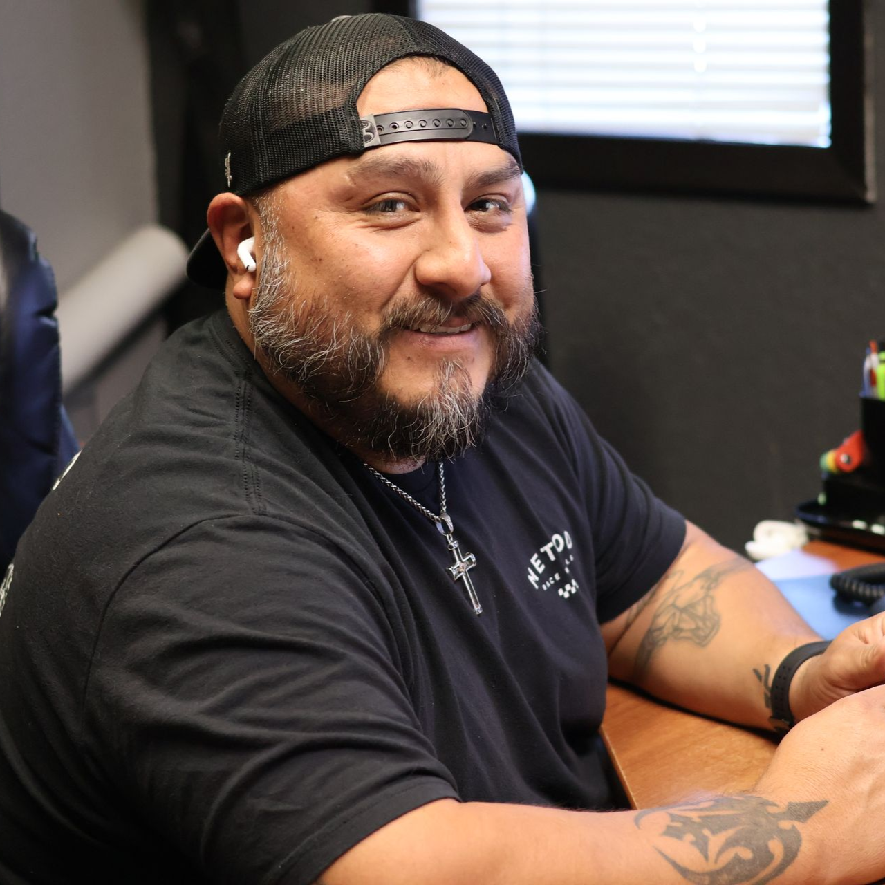 Ben Delgado in a black shirt and cap seated at a desk in the TSD office