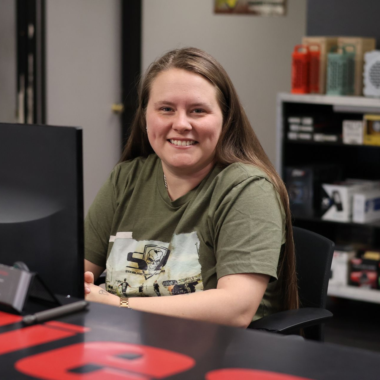 Cheyenne Alexander seated at a desk in the TSD office, wearing a green T-shirt and facing a computer monitor.