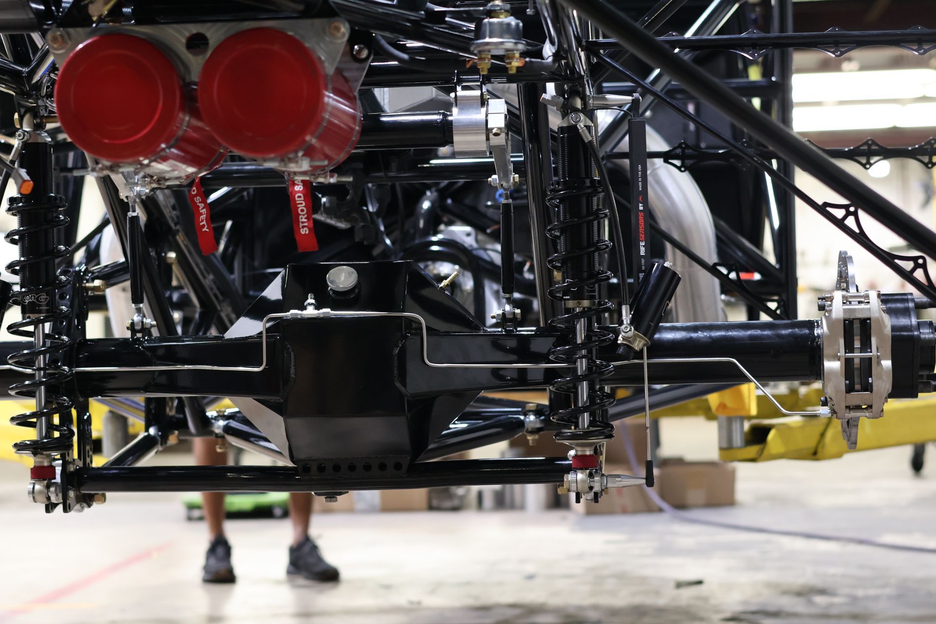Rear view of a yellow race car chassis with red taillights in a garage