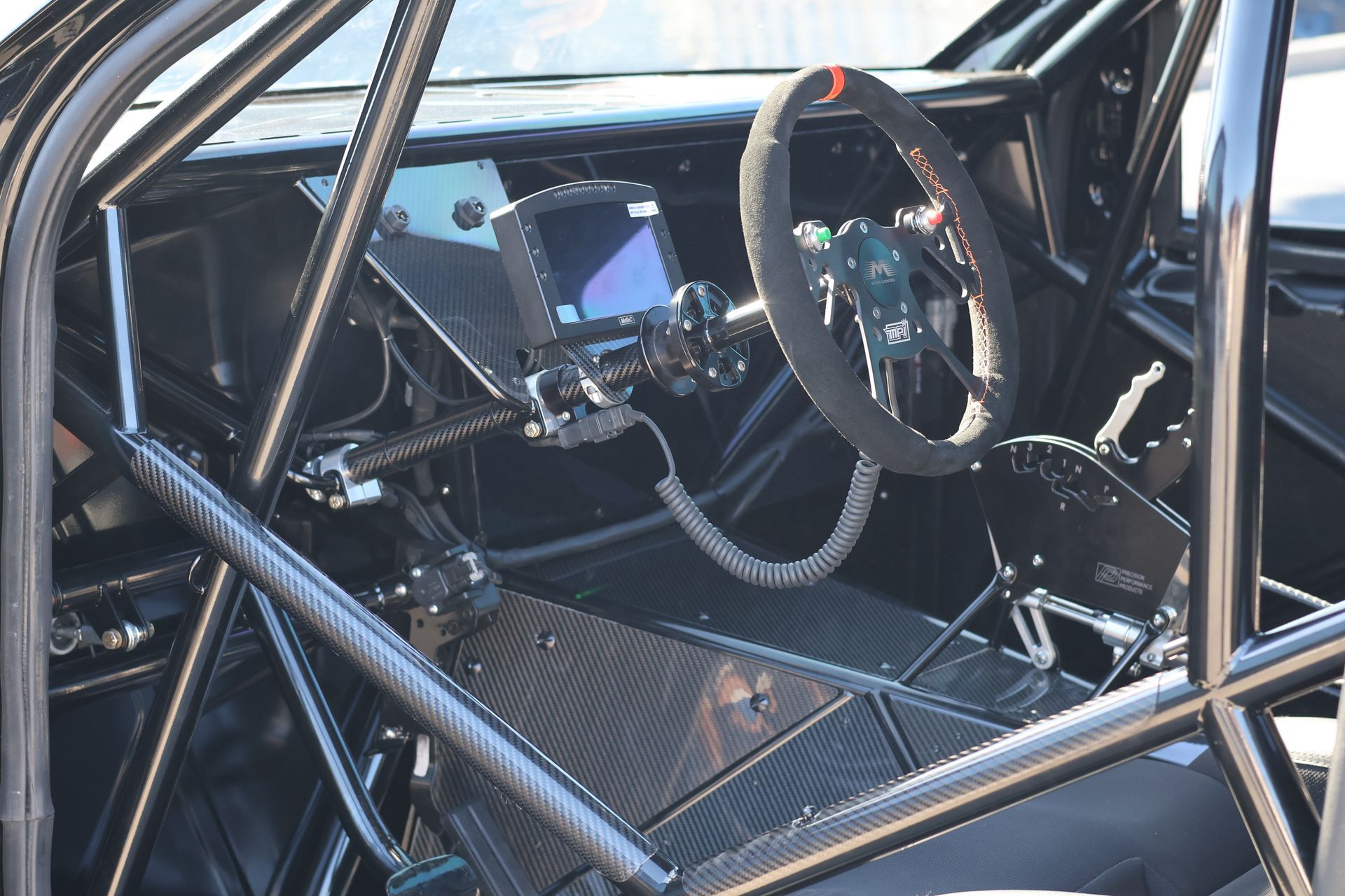 Interior of a race car with a roll cage, steering wheel, and dashboard visible