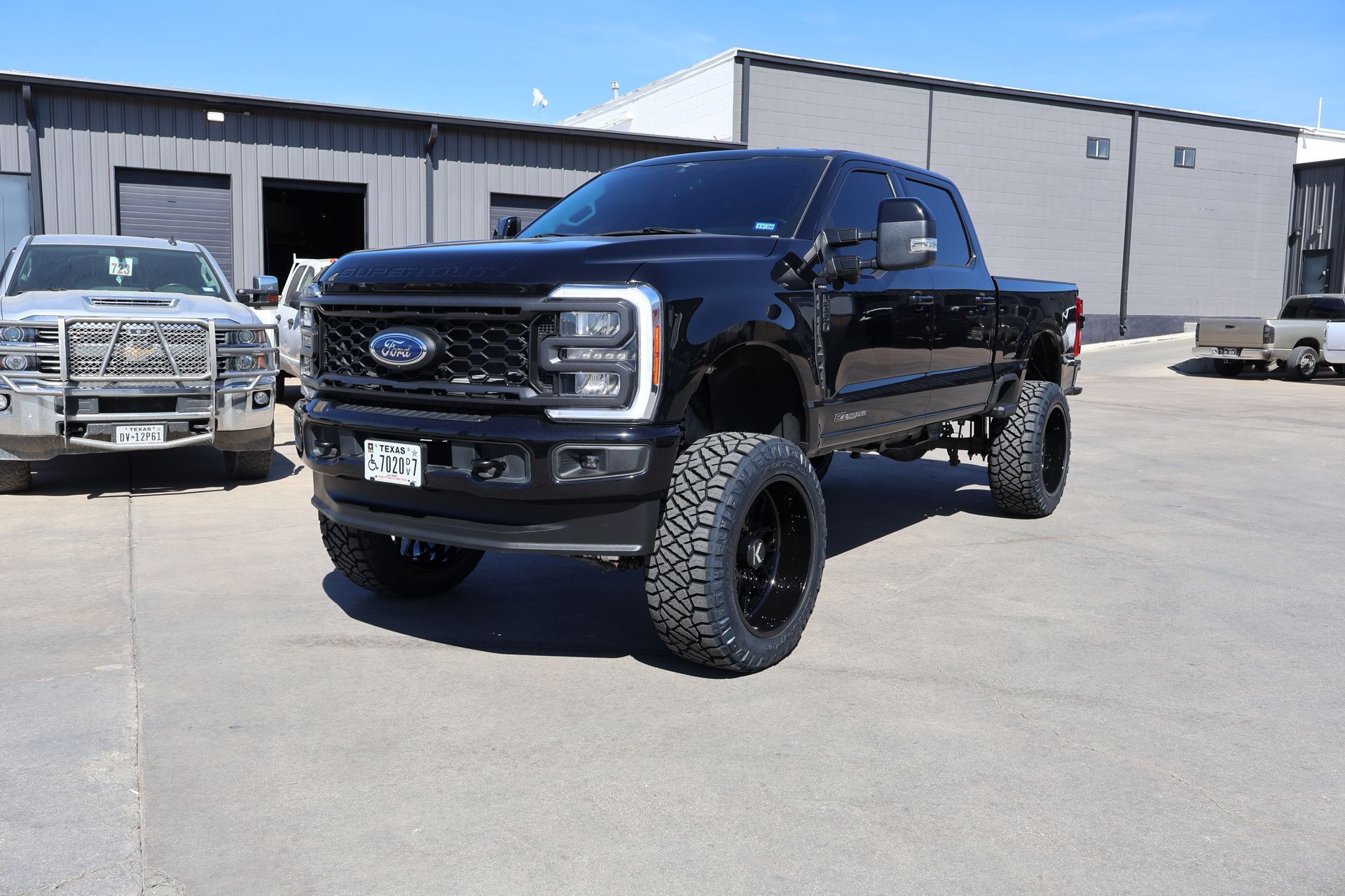 Black lifted Ford pickup truck parked outside an industrial building