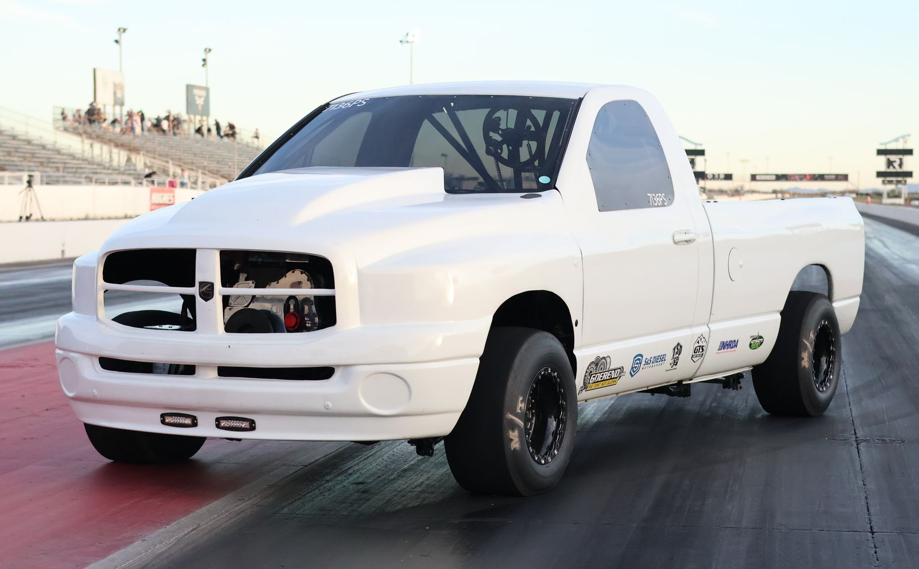 White diesel-powered race truck named Opie on a racetrack, front three-quarter view with black wheels and decals
