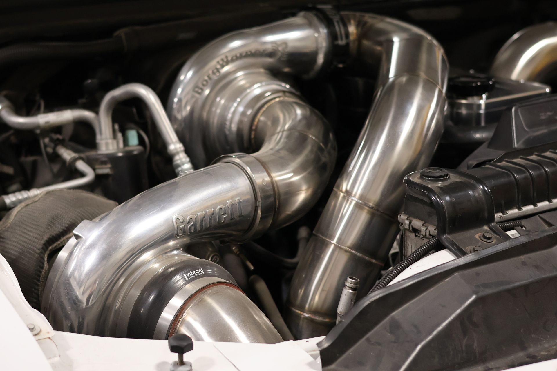 Shiny stainless steel turbo exhaust pipes in a car engine bay
