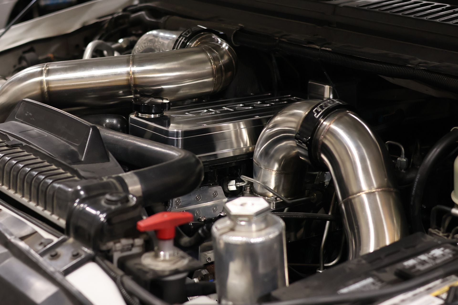 Shiny car engine bay with polished metal pipes and black components
