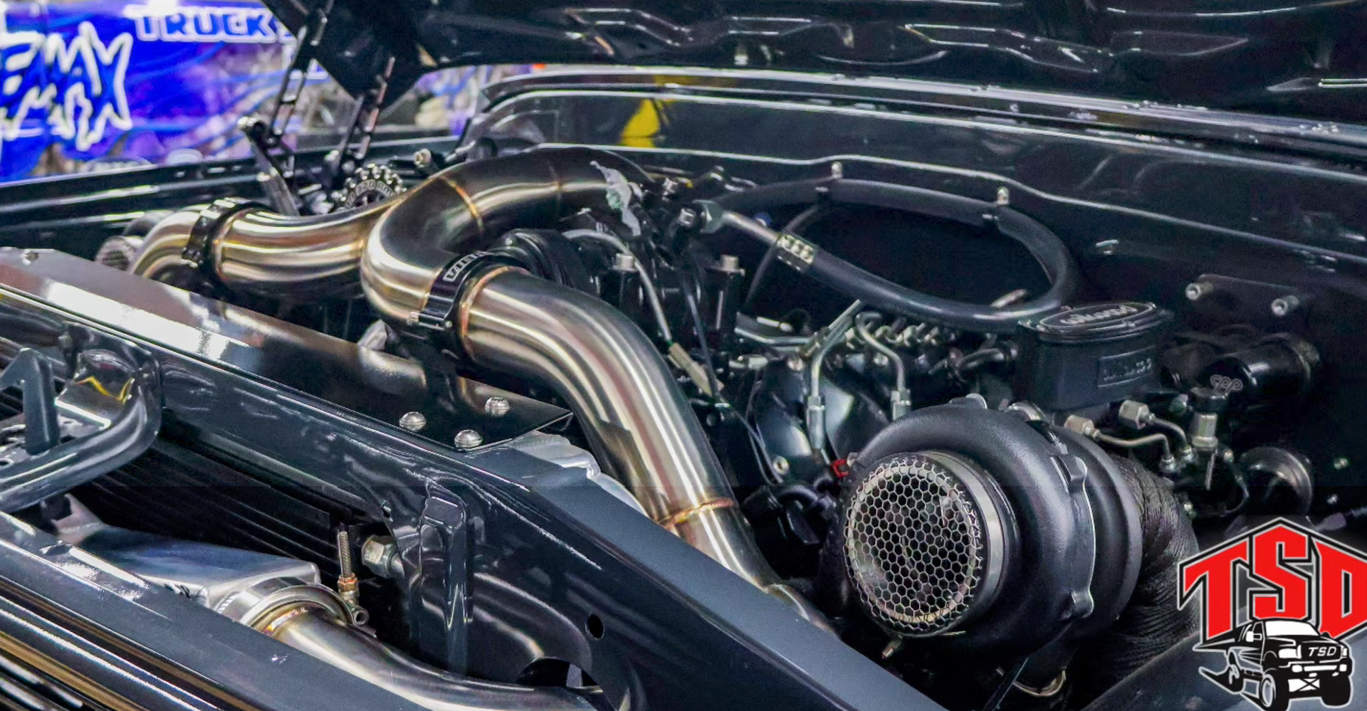 Custom turbocharged car engine with polished pipes and twin turbo setups under the hood