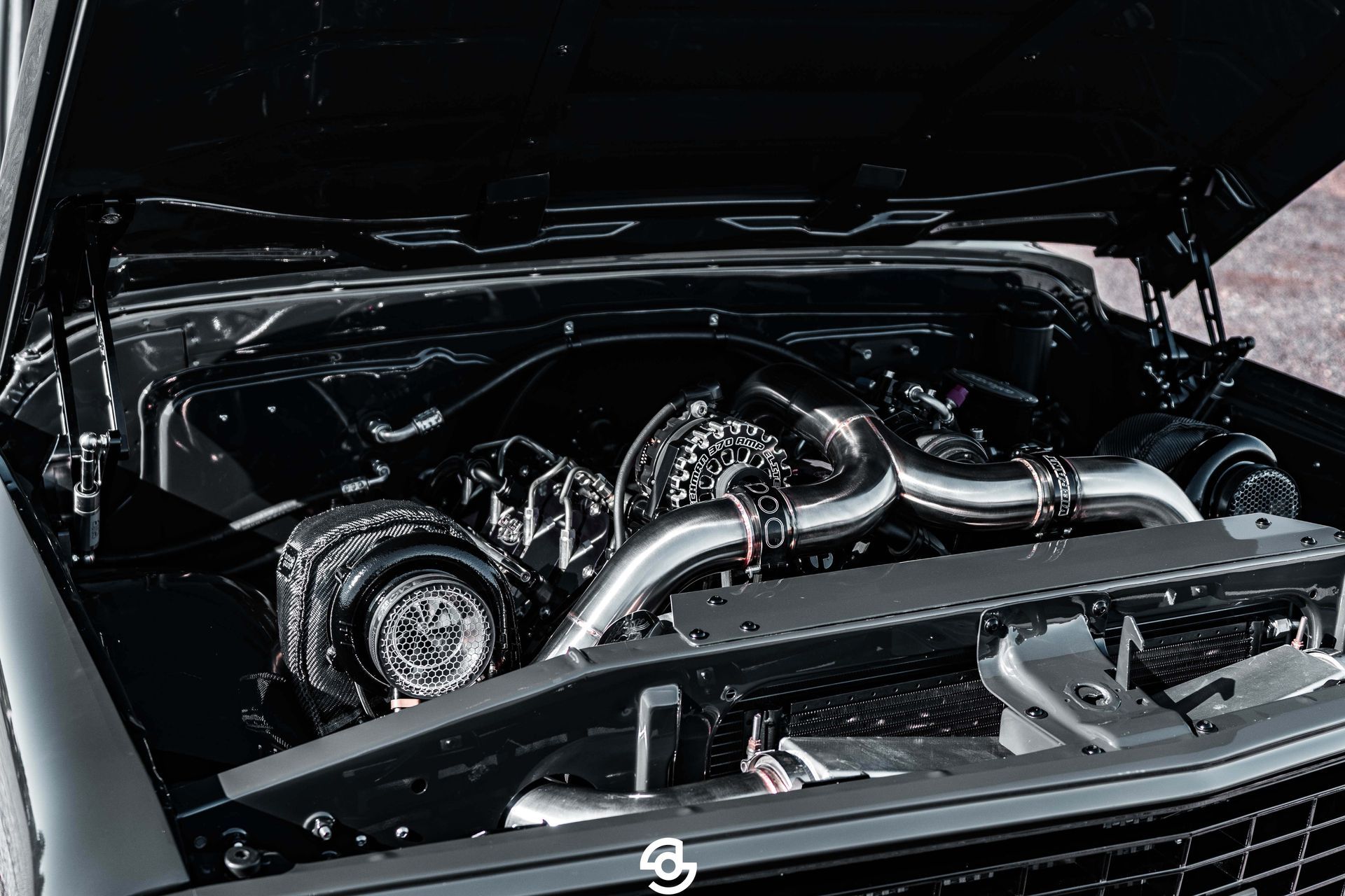 Black car engine bay with a polished custom turbo setup under the hood