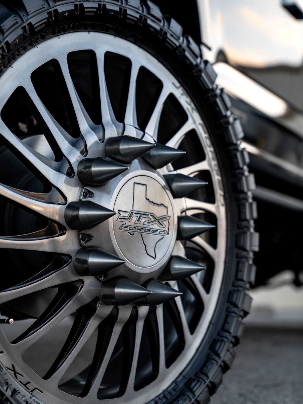 Close-up of a black off-road tire and silver alloy wheel with a center cap emblem.