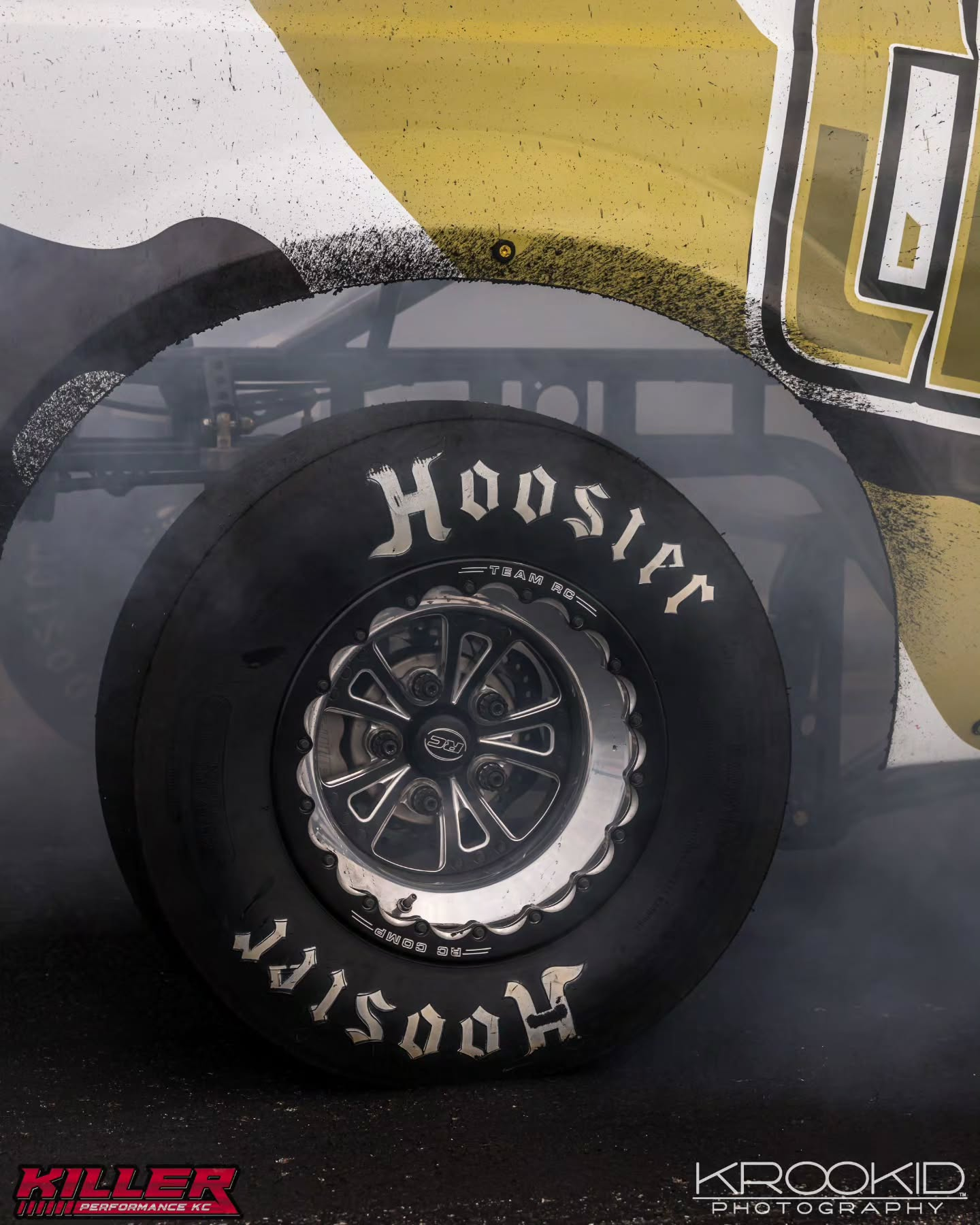 Close-up of a black Hoosier racing tire on a yellow-and-black vehicle