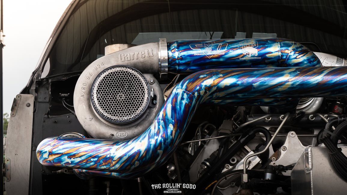 Blue iridescent engine piping with a white turbocharger in a car engine bay