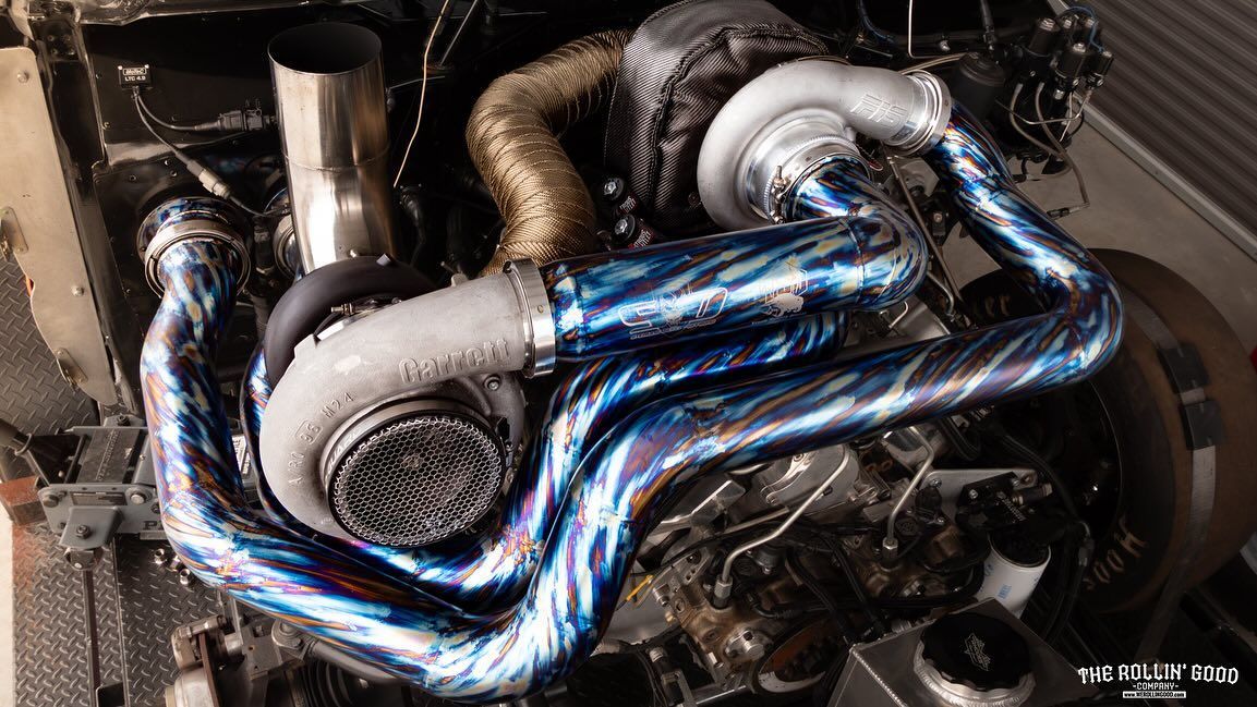 Close-up of an engine bay with shiny blue heat-wrapped exhaust pipes and turbo components